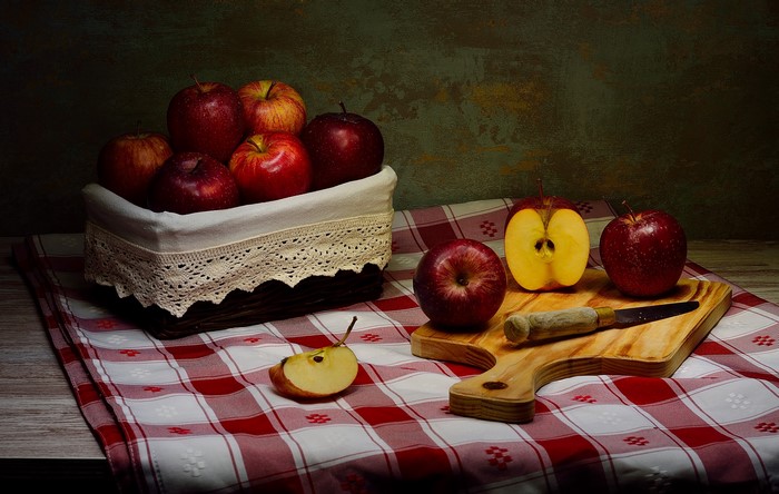 Apples in a basket and on a cutting board with a knife