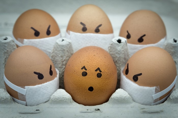 Eggs with faces and masks in a carton