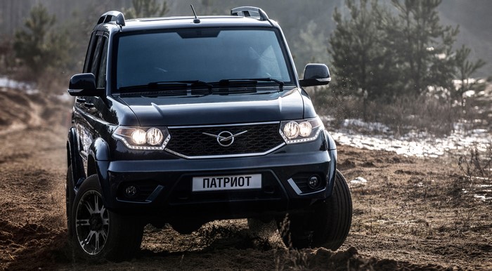 Black 2016 UAZ Patriot SUV driving on dirt road