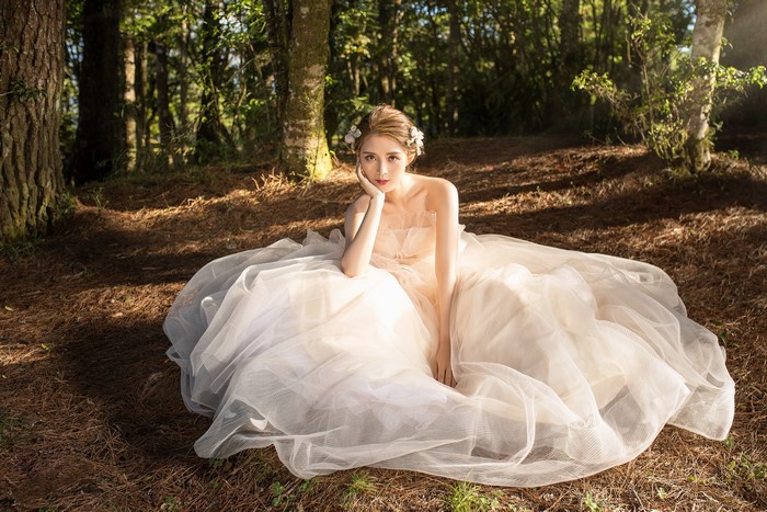 Bride in a white dress sitting in a forest