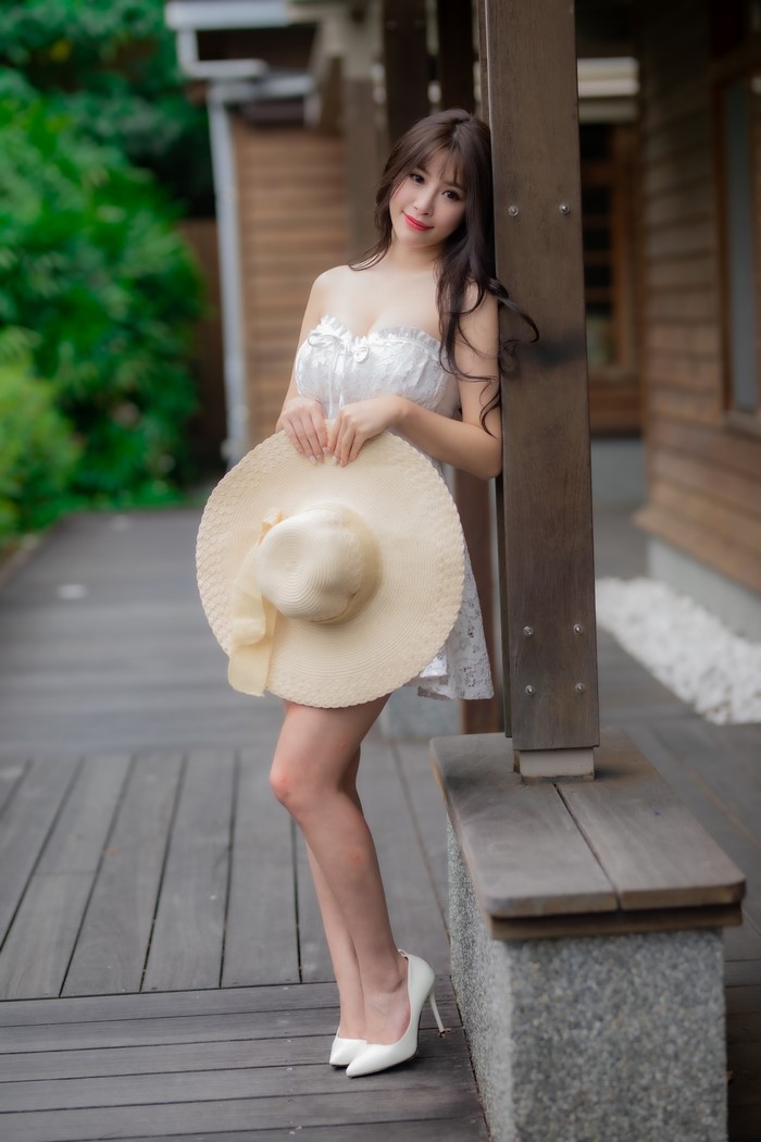 Asian woman in white dress holding a hat
