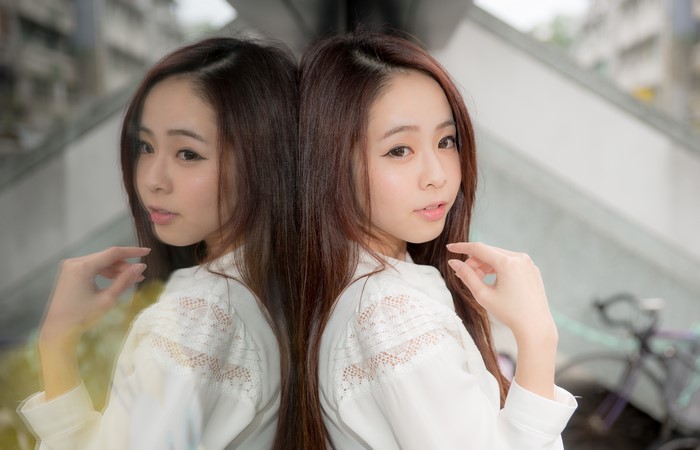 Asian woman with brown hair reflected in glass