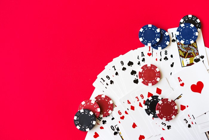 Casino chips and playing cards on red background