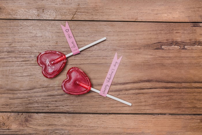 Two heart-shaped lollipops on wood planks