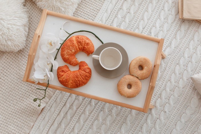 Breakfast tray with croissants, donuts, and orchid