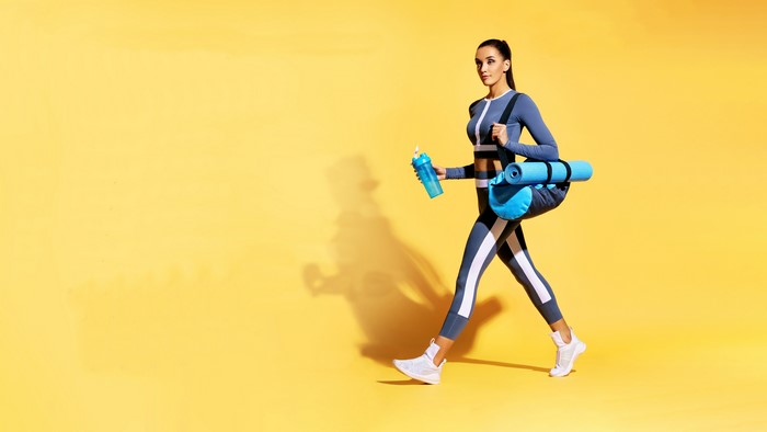 Woman in fitness attire with yoga mat and water bottle