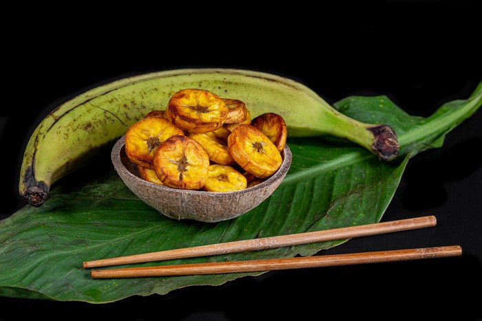 Fried Plantain Chips in Coconut Bowl with Plantain and Chopsticks