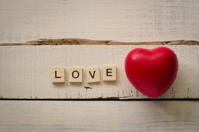 Love spelled with wooden letters next to a red heart