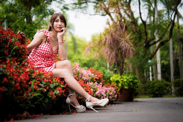 Asian woman in red and white dress sitting by flowers