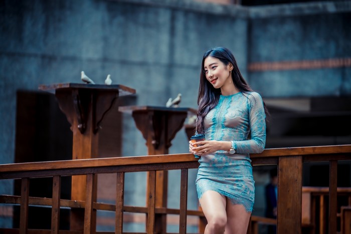 Asian woman in a blue dress holding a coffee cup
