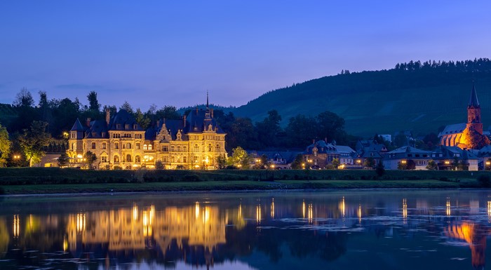 Castle and church by river at dusk in Germany