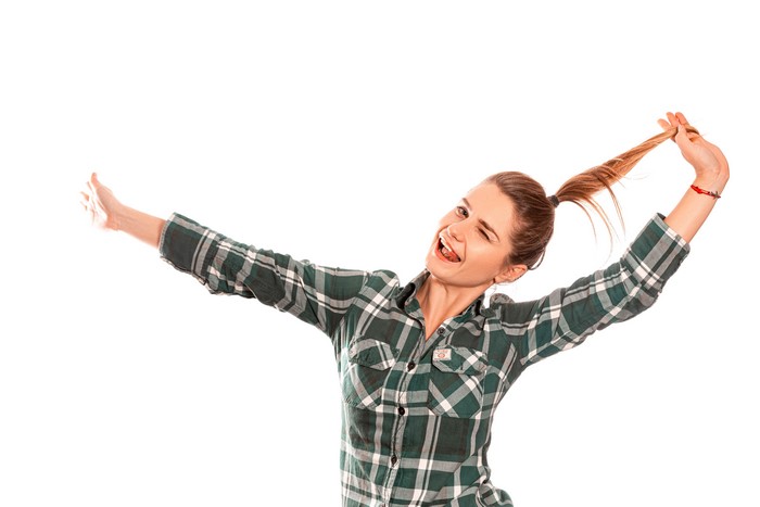 Woman in plaid shirt playing with her ponytail