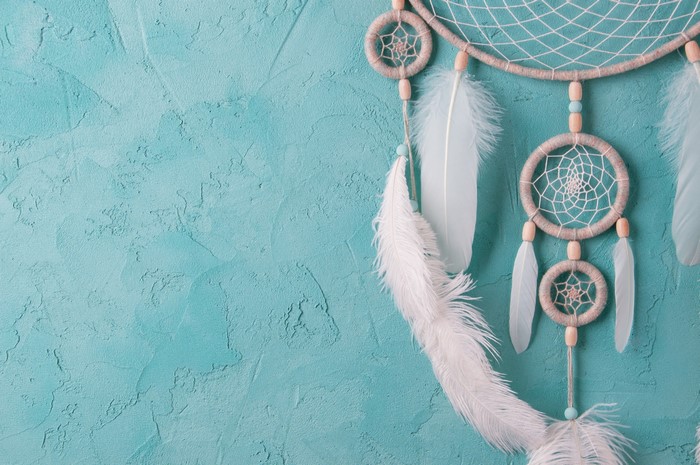 Dreamcatcher with feathers on a textured blue wall