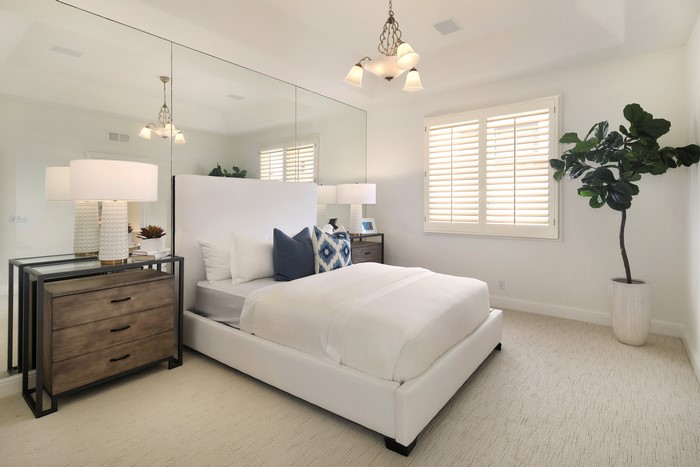 Bedroom with white bed, lamps, and mirrored wall