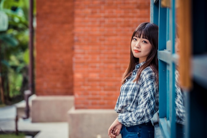 Asian woman in plaid shirt leaning against blue frame