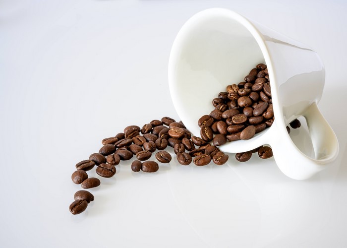 Coffee beans spilling from a mug