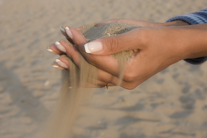 Hands letting sand fall on a beach