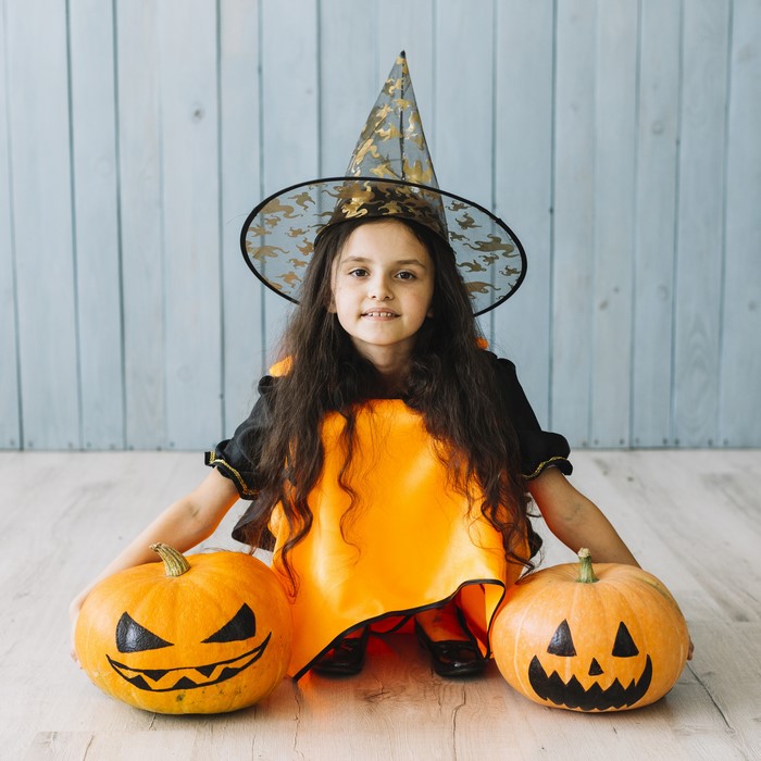 Girl in witch costume with pumpkins