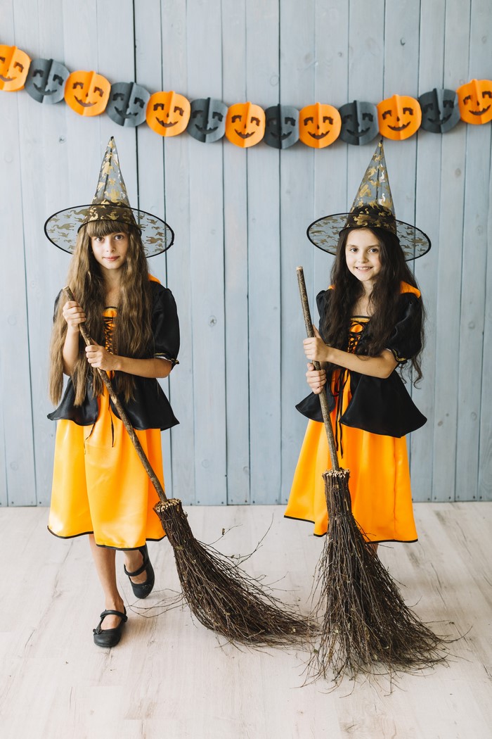 Two girls in witch costumes with brooms