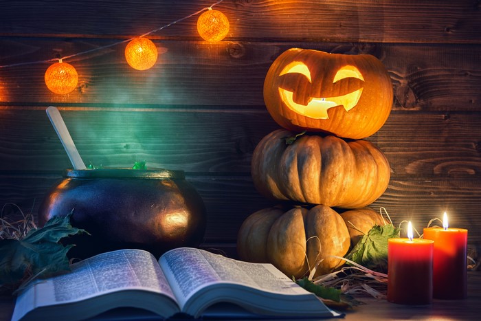 Halloween still life with pumpkins, cauldron, book, and fairy lights