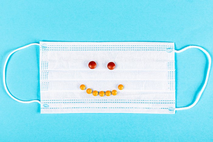 Face mask with pills forming a smiley face
