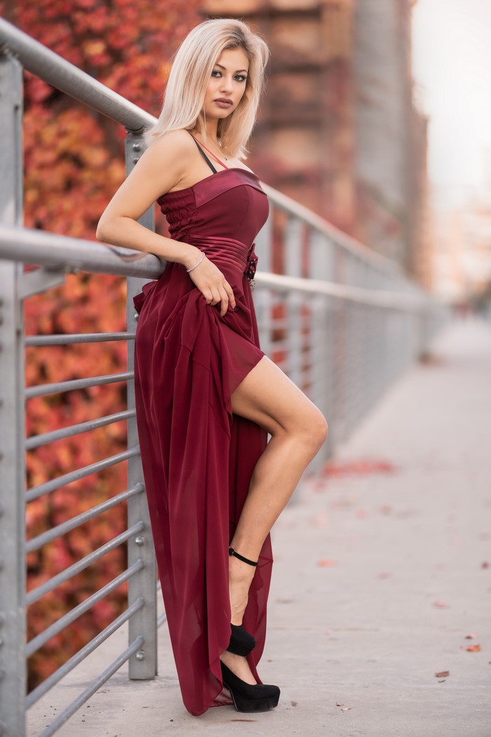 Blonde woman in a burgundy dress on a bridge