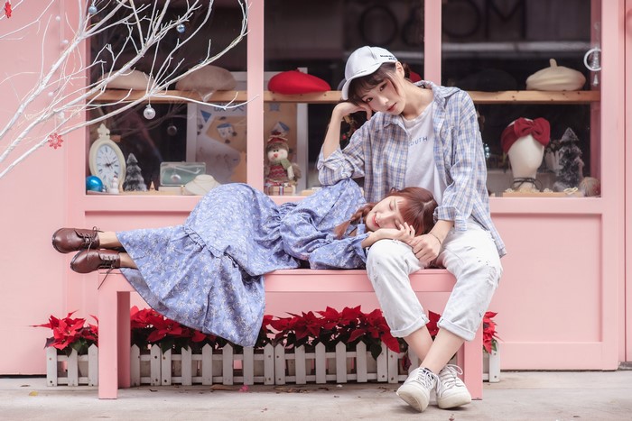 Two Asian women sitting and lying on a pink bench