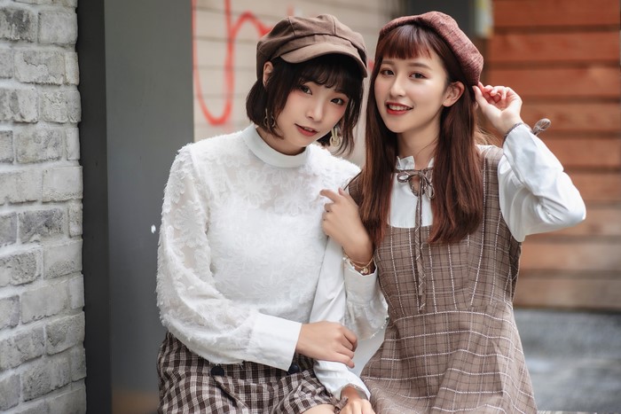 Two Asian women wearing berets and plaid outfits