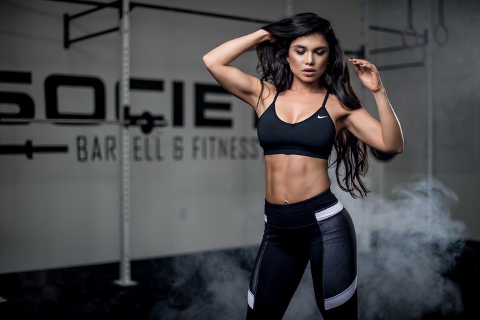 Woman in Nike sports bra and leggings posing in gym