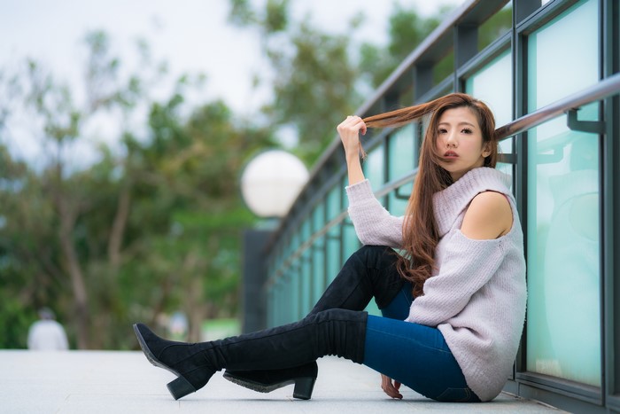 Asian woman with brown hair wearing a sweater and boots