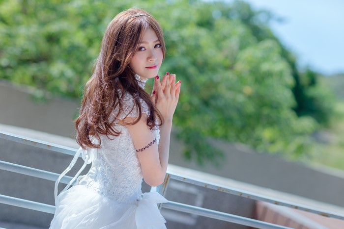 Asian woman in white dress with hands clasped