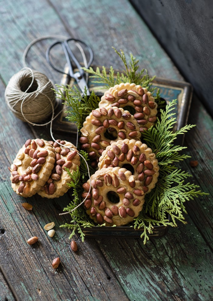 Peanut cookies with evergreen branches on wooden table