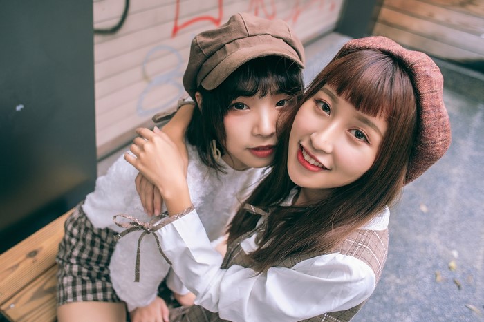 Two Asian girls hugging and wearing berets