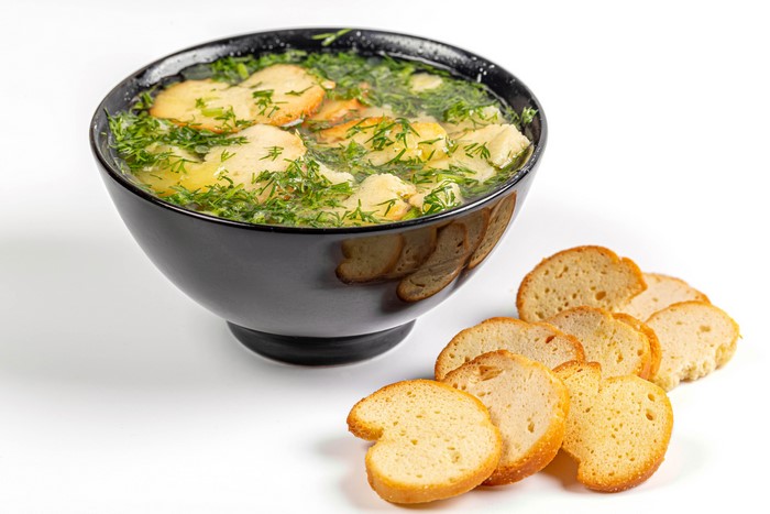 Soup with dill and bread on white background