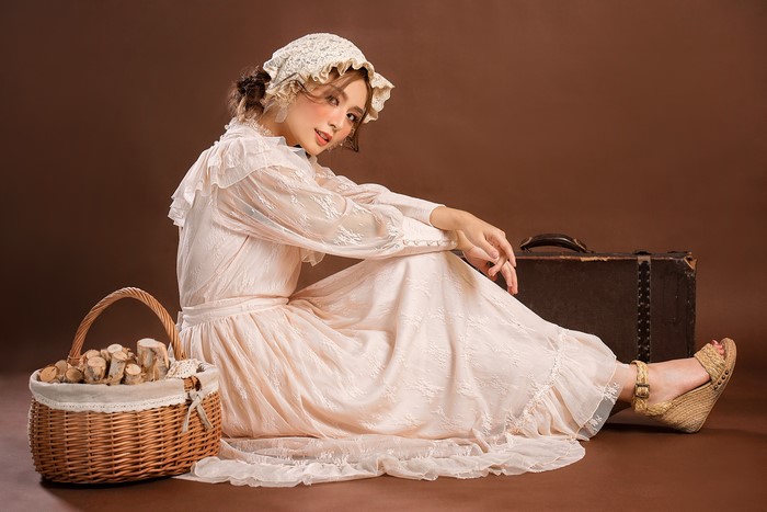 Asian woman in retro dress with suitcase and basket