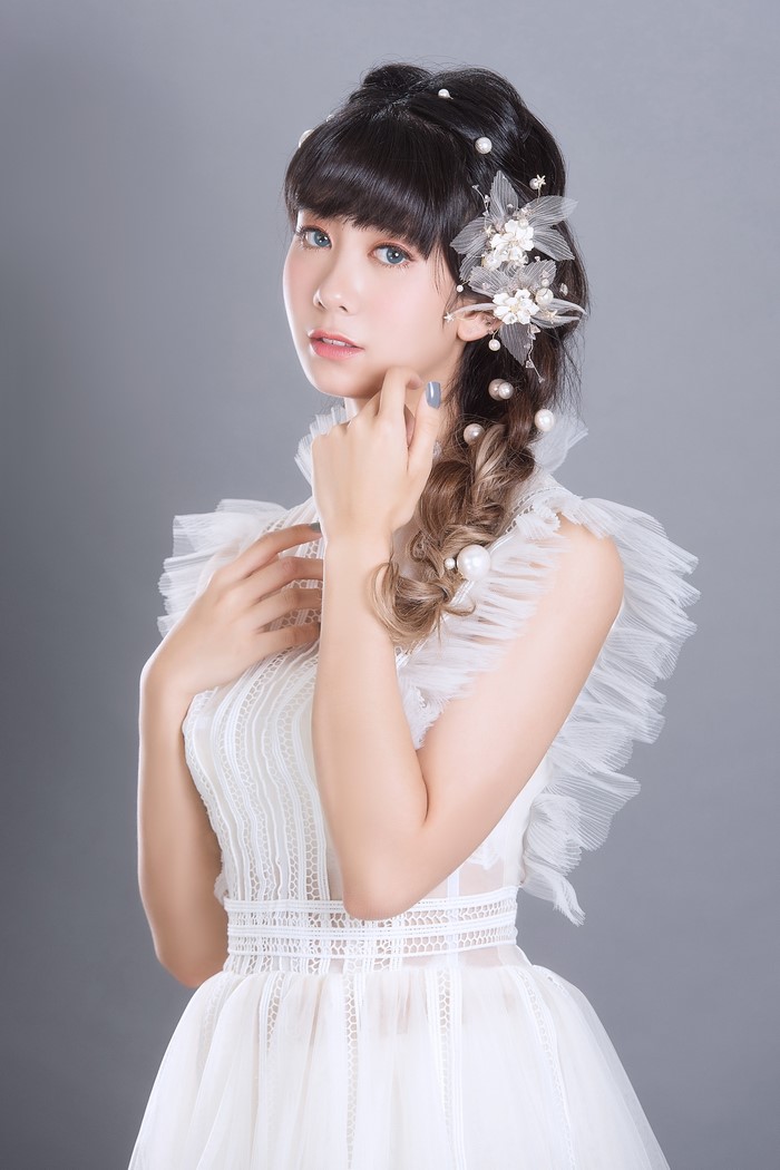 Asian woman with braided hair and pearl accessories in a white dress