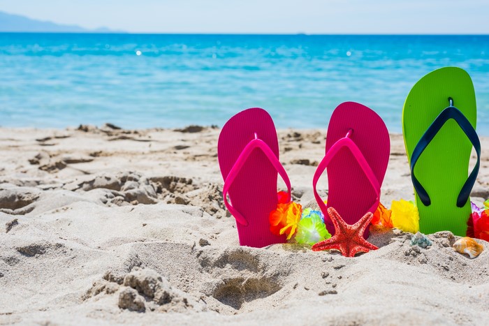 Flip-flops on a sandy beach with the ocean in the background
