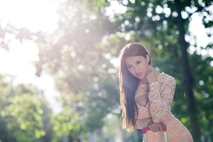 Asian woman in a pink dress with a suitcase
