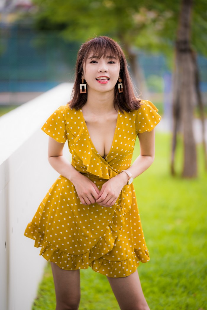 Asian woman in yellow polka dot dress sticking tongue out
