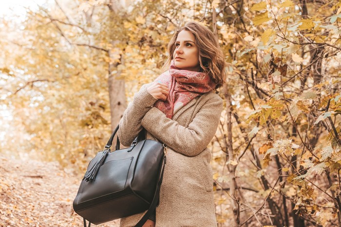Woman with handbag in autumn forest