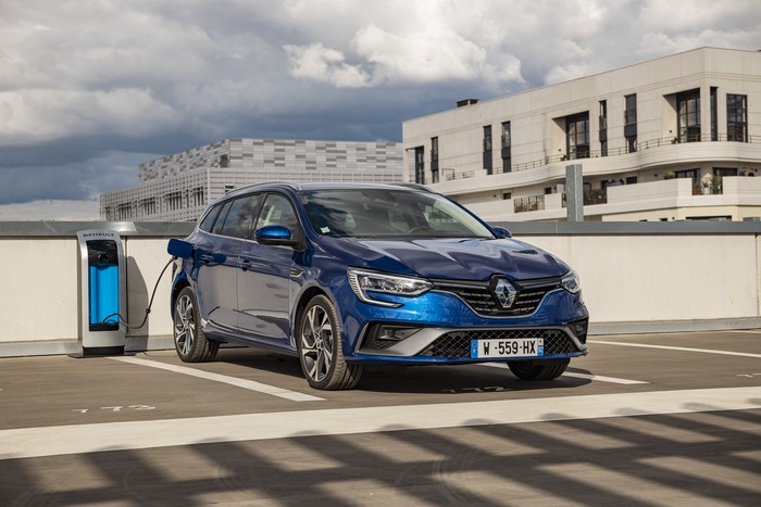 Blue Renault hybrid car charging at a station