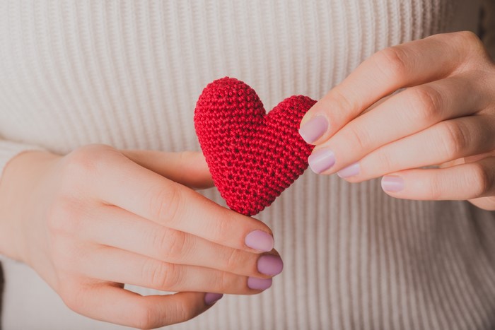 Hands holding a red knitted heart