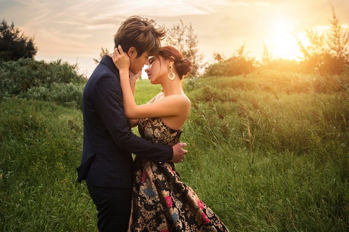 Couple embracing in a grassy field at sunset