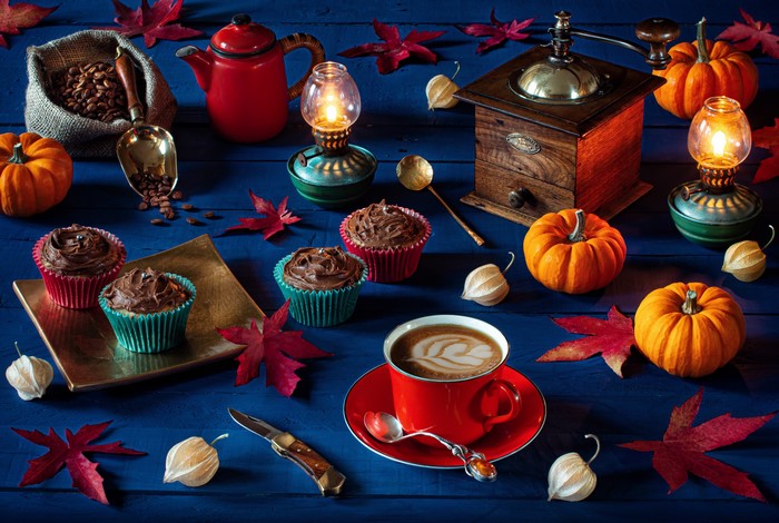 Still-life with coffee, cupcakes, pumpkins, and autumn leaves