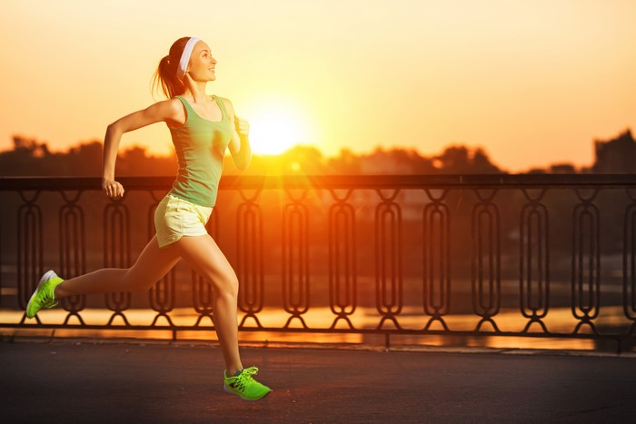 Woman running on a bridge at sunset