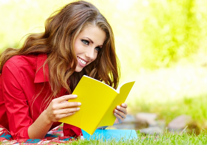 Woman reading a yellow book on the grass