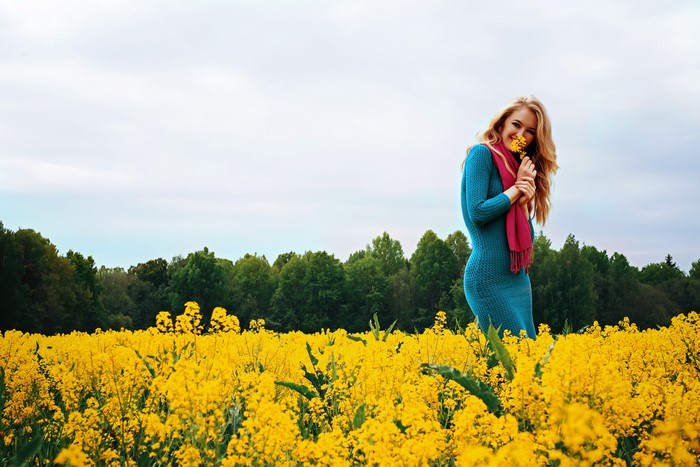 Blonde girl in a field of yellow flowers