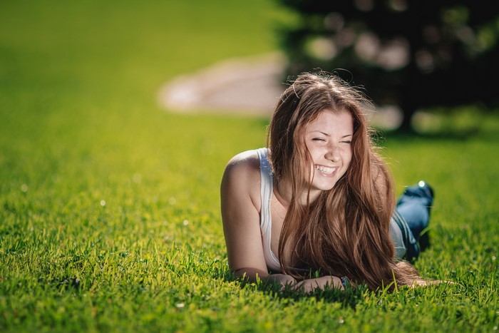 Brown haired girl lying on grass and smiling