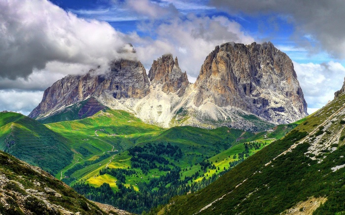 Jagged mountain peaks with green valleys and clouds