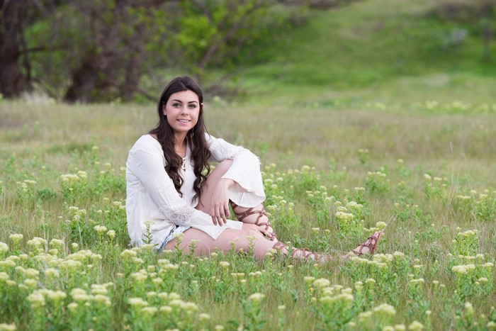 Brunette girl sitting in a grassy field